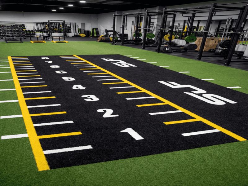 Engineer inspecting UV-resistant gym turf under direct sunlight